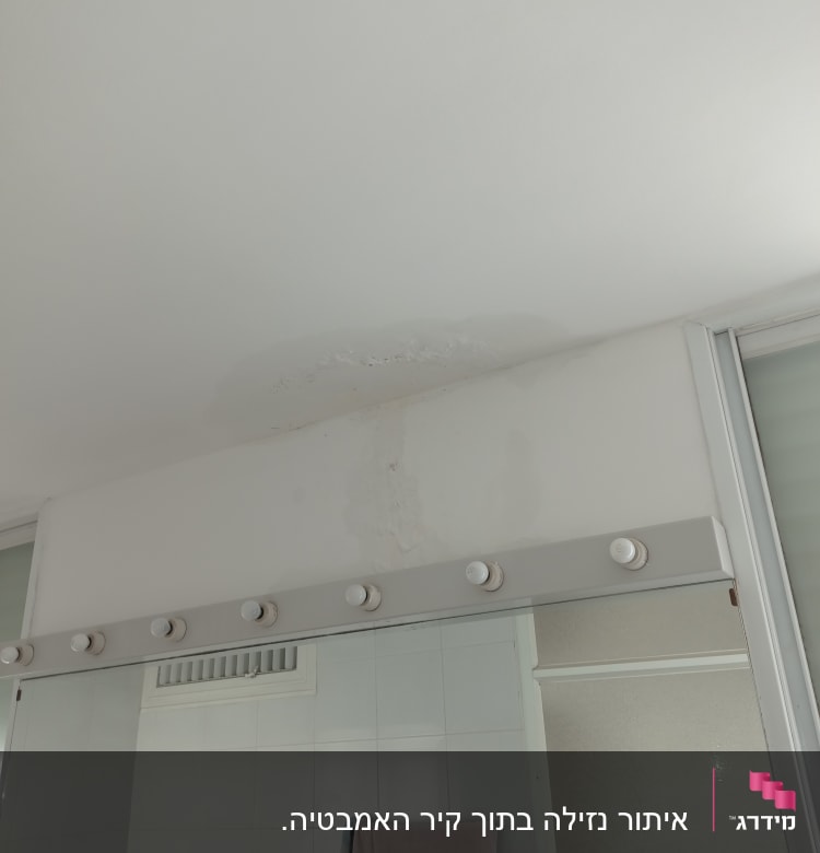 כתם רטיבות בתקרה מעל מראה בחדר אמבטיה